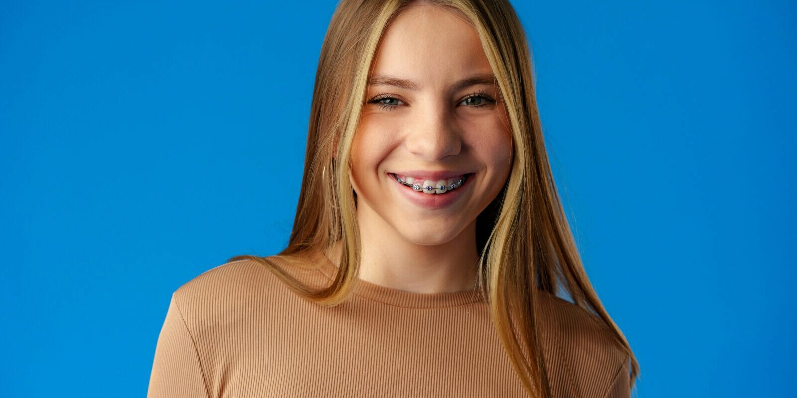 Happy teenager, positive smiling girl on blue background in studio Happy teenager, positive smiling girl on blue background in studio close up